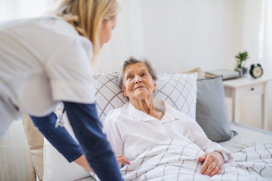 Caregivers for seniors helping elderly woman in home bedroom in Erie, PA